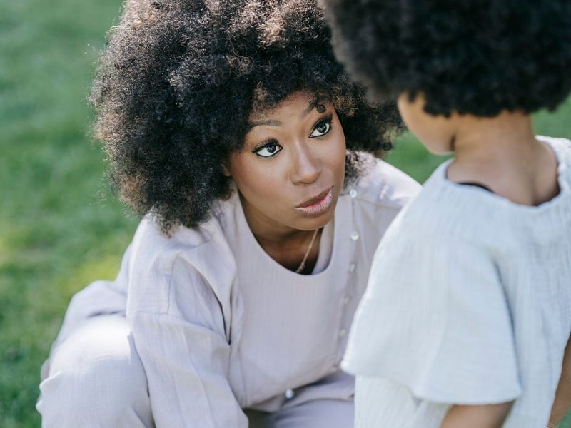 Mãe agachada conversando com a criança na altura dos olhos